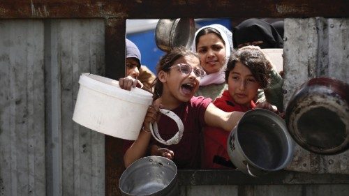 Palestinian children gesture as they line up to collect a meal at a free food distribution point in ... Palestinian children gesture as they line up to collect a meal at a free food distribution point in ...