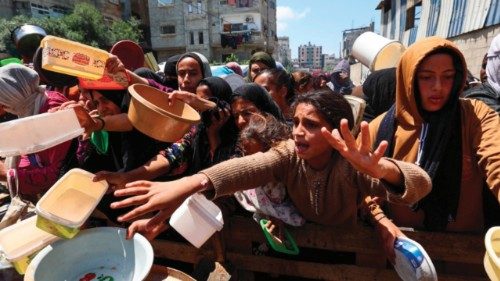 Displaced Palestinians scuffle for a portion of hot food at a charity kitchen at the Nuseirat ... Displaced Palestinians scuffle for a portion of hot food at a charity kitchen at the Nuseirat ...