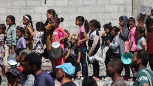 Palestinians gather to receive a hot meal at a food distribution point in the Nuseirat camp for ... Palestinians gather to receive a hot meal at a food distribution point in the Nuseirat camp for ...