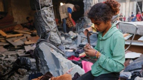 A girl collects belongings as Palestinians check the site of an overnight Israeli strike, in Jabalia ... A girl collects belongings as Palestinians check the site of an overnight Israeli strike, in Jabalia ...