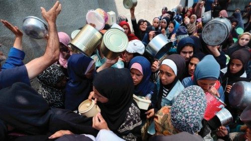 Palestinian women gather at a hot meal distribution point in Nuseirat in the central Gaza Strip, ...