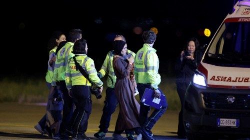 A woman carrying a child walks towards an ambulance, after the aircraft carrying Adam Al-Najjar, a ... A woman carrying a child walks towards an ambulance, after the aircraft carrying Adam Al-Najjar, a ...