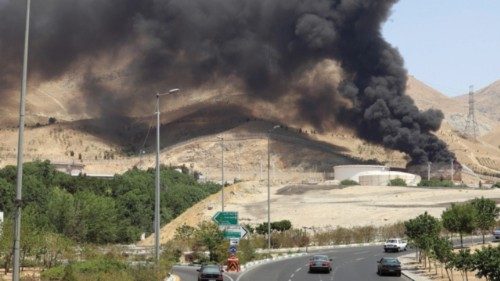 epa12178553 Cars drive along a motorway as smoke rises in the background from an oil refinery, ...