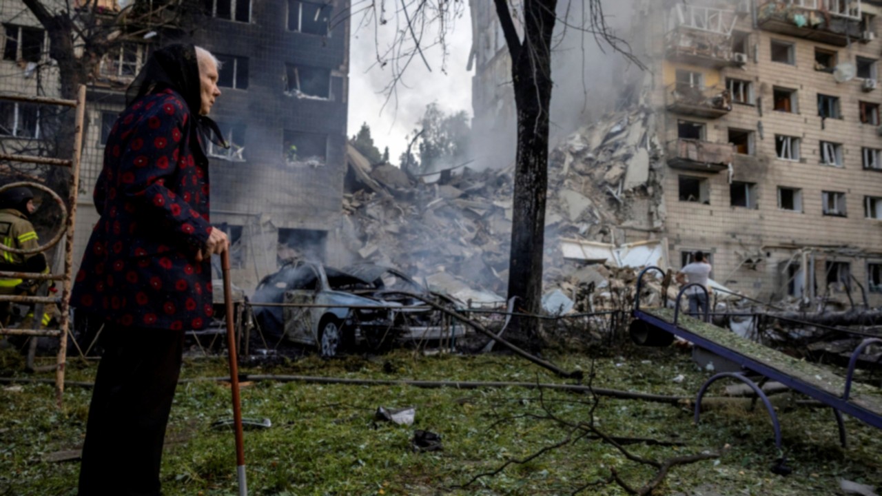 A woman looks at a partially collapsed apartment building after a Russian missile strike, amid ...