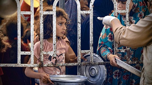 TOPSHOT - Palestinians child waits in front of a hot meal distribution kitchen in Rafa's al-Mawasi ...
