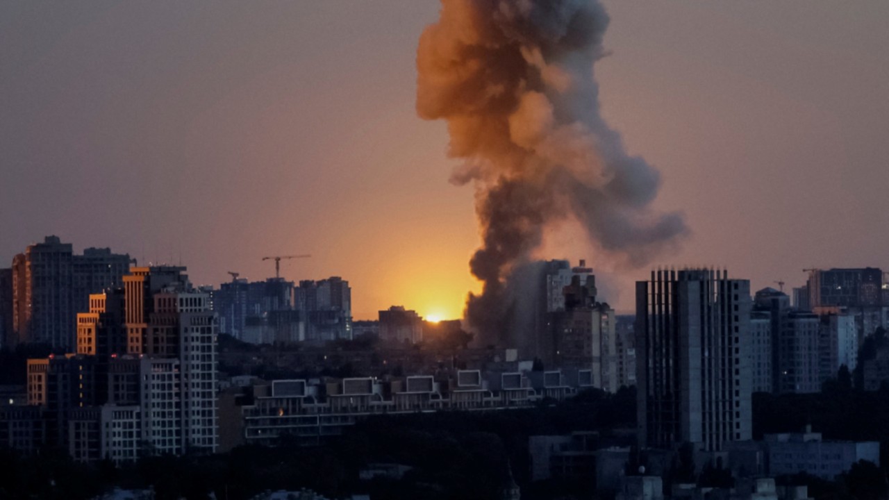An explosion of a missile lights up the sky over the city during a Russian drone and missile strike, ...
