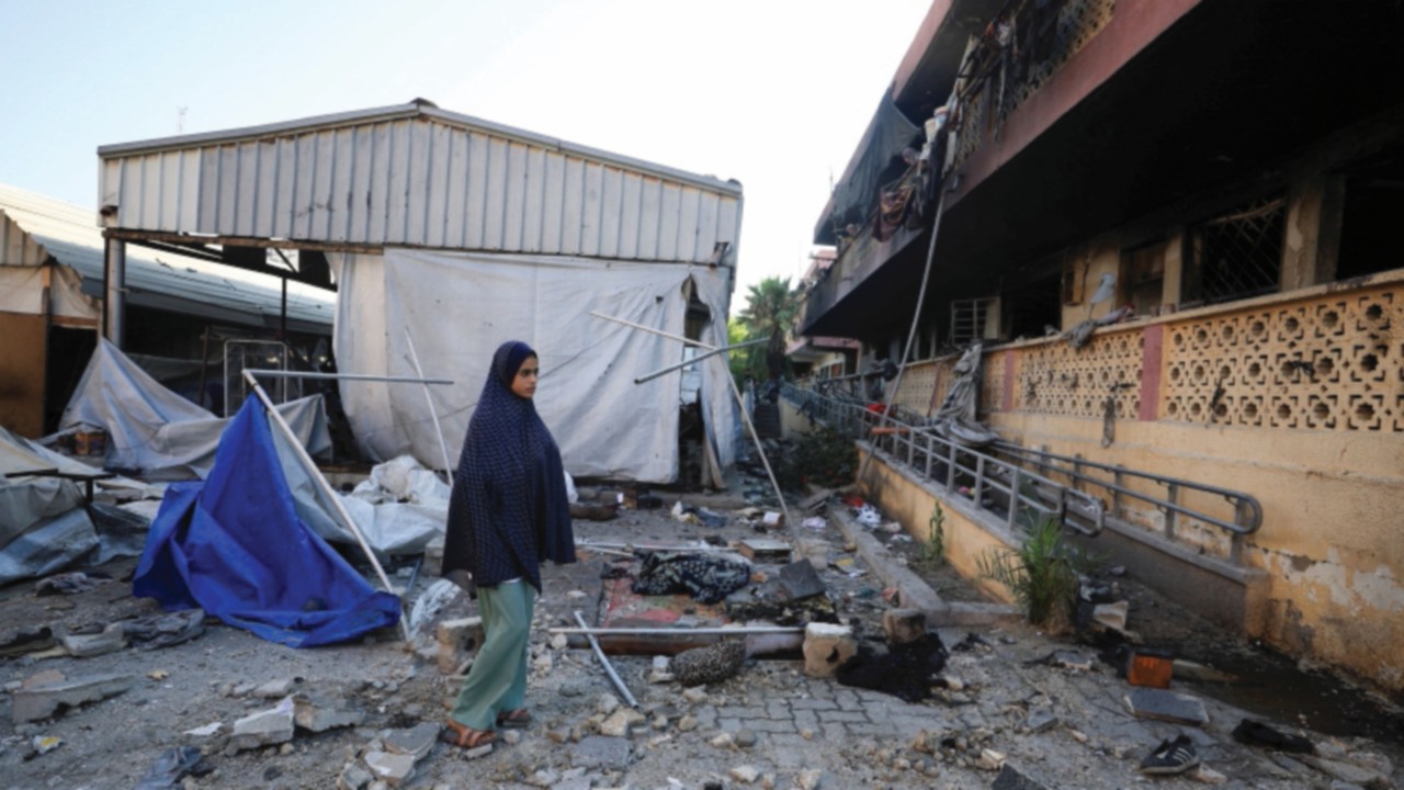A Palestinian inspects the damage at a school sheltering displaced people, following an overnight ...