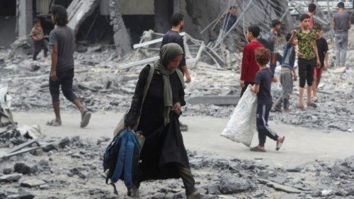 A Palestinian woman walks at the damaged site of an UNRWA school sheltering displaced people that ... A Palestinian woman walks at the damaged site of an UNRWA school sheltering displaced people that ...