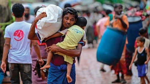 In this photo taken on September 12, 2024, a Rohingya refugee man holds his child while carrying ... In this photo taken on September 12, 2024, a Rohingya refugee man holds his child while carrying ...
