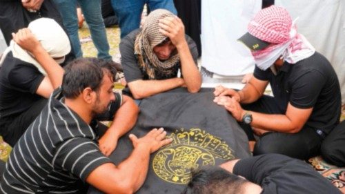 Iraqis mourn over the coffin of a relative, killed in a shopping mall fire in the city of Kut, ...