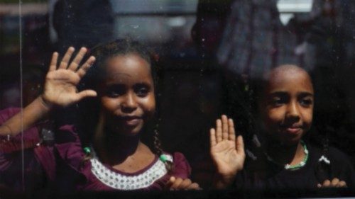 Children look outside from a train window as Sudanese families displaced by conflict return home ...