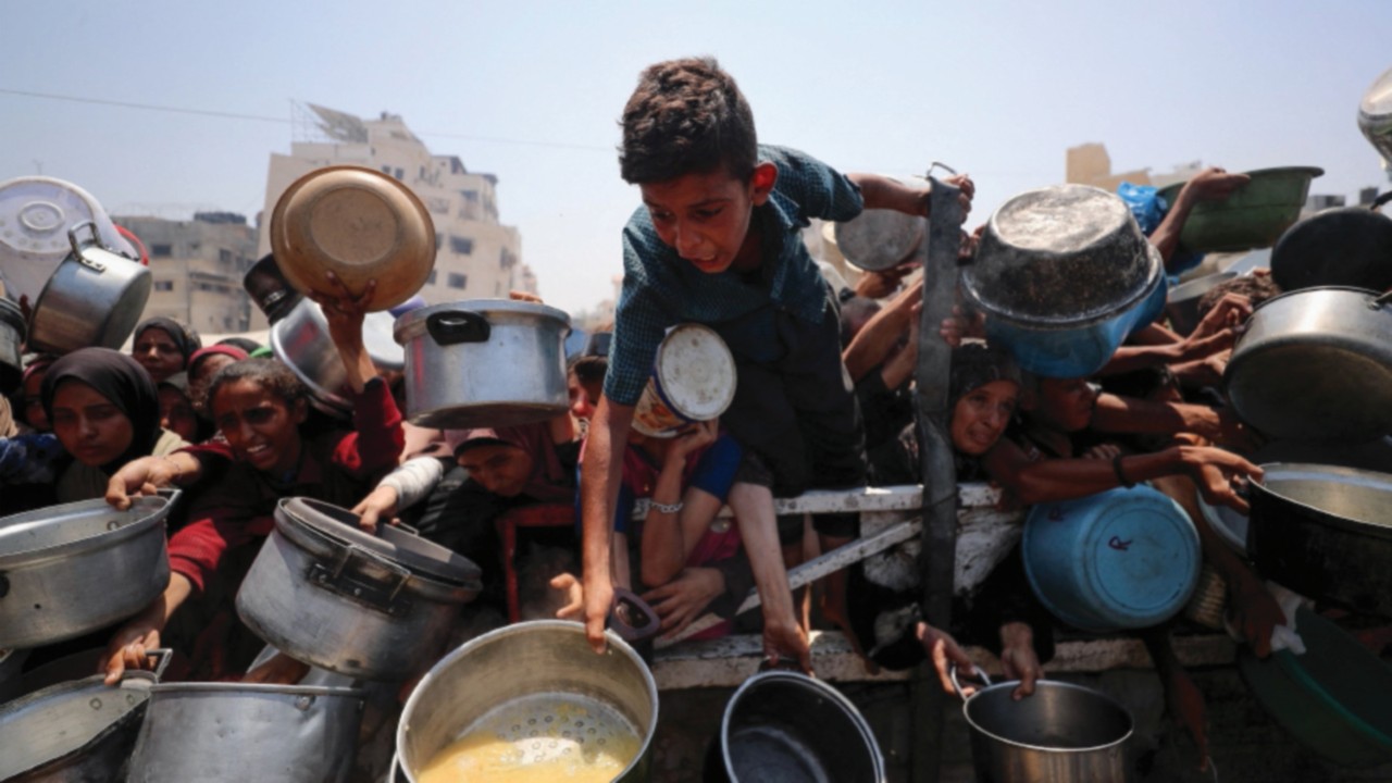 Palestinians wait to receive food from a charity kitchen, amid a hunger crisis, in Gaza City, July ...