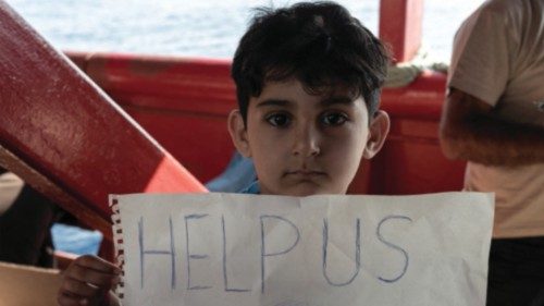 A migrant child holds a sign on board the Ocean Viking ship sailing in the Strait of Sicily in the ...
