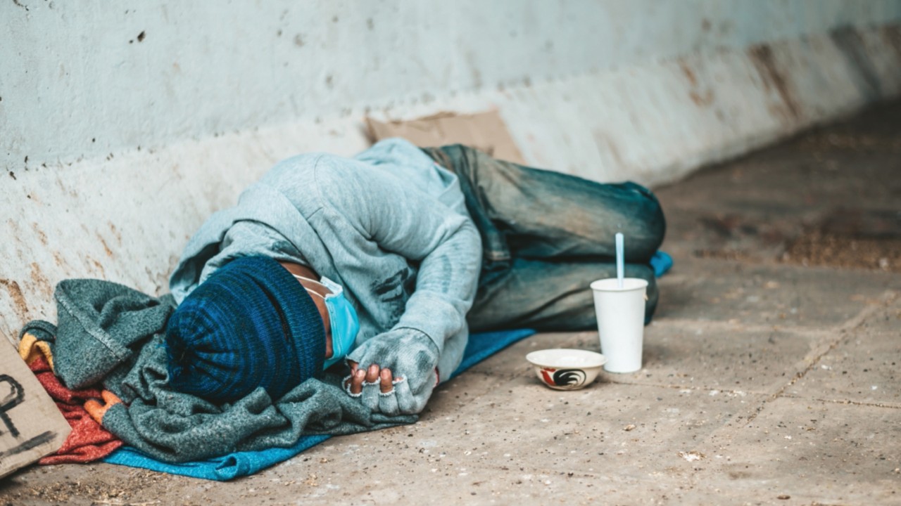 The beggars lay on their side of the street with dirty clothes.