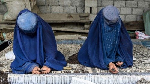 TOPSHOT - Afghan refugee burqa-clad women tailor a carpet at the Khurasan refugee camp on the ...