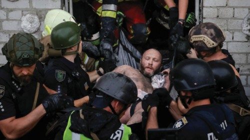 Rescuers and police officers carry a man rescued from debris at the site of an apartment building ...