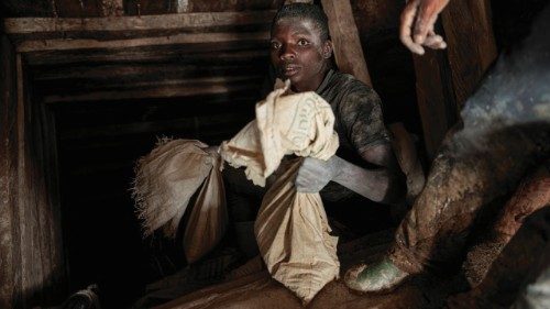 A miner holds a sack of ore as it comes out from the mine shaft at Rubaya coltan mine, near the town ...