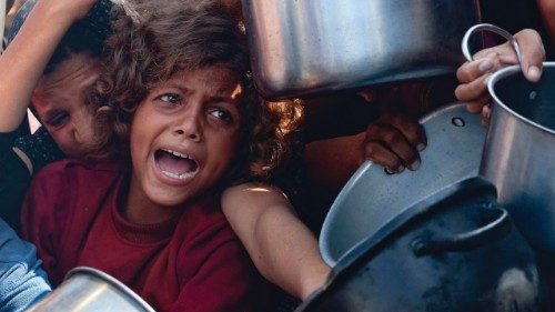 Palestinian women and children hold out their empty pots in front of a charity kitchen in Khan Yunis ...