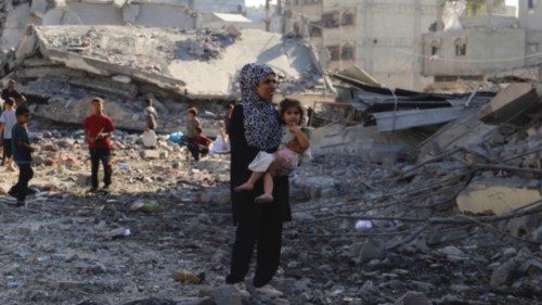 A Palestinian woman carries a child, as they inspect the site of an overnight Israeli strike on a ... A Palestinian woman carries a child, as they inspect the site of an overnight Israeli strike on a ...