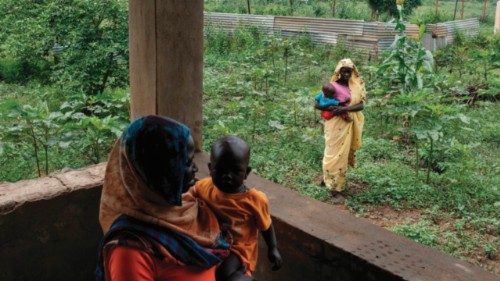Women wait with their children to be measured for aid near a reception centre for new arrivals from ...