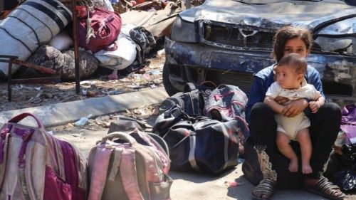 A Palestinian girl holds a child next to belongings laying on the ground, as displaced Palestinians ... A Palestinian girl holds a child next to belongings laying on the ground, as displaced Palestinians ...