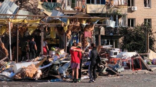 Local residents embrace each other next to a damaged residential building following an air attack in ... Local residents embrace each other next to a damaged residential building following an air attack in ...