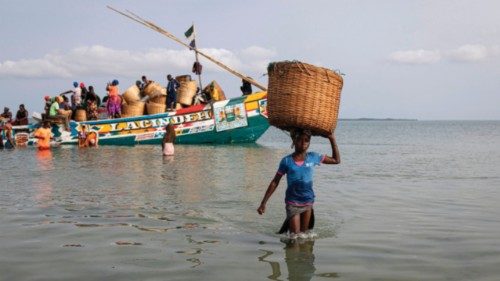 A girl carries a basket on her head full of goods after unloading them from a pirogue bringing ... A girl carries a basket on her head full of goods after unloading them from a pirogue bringing ...