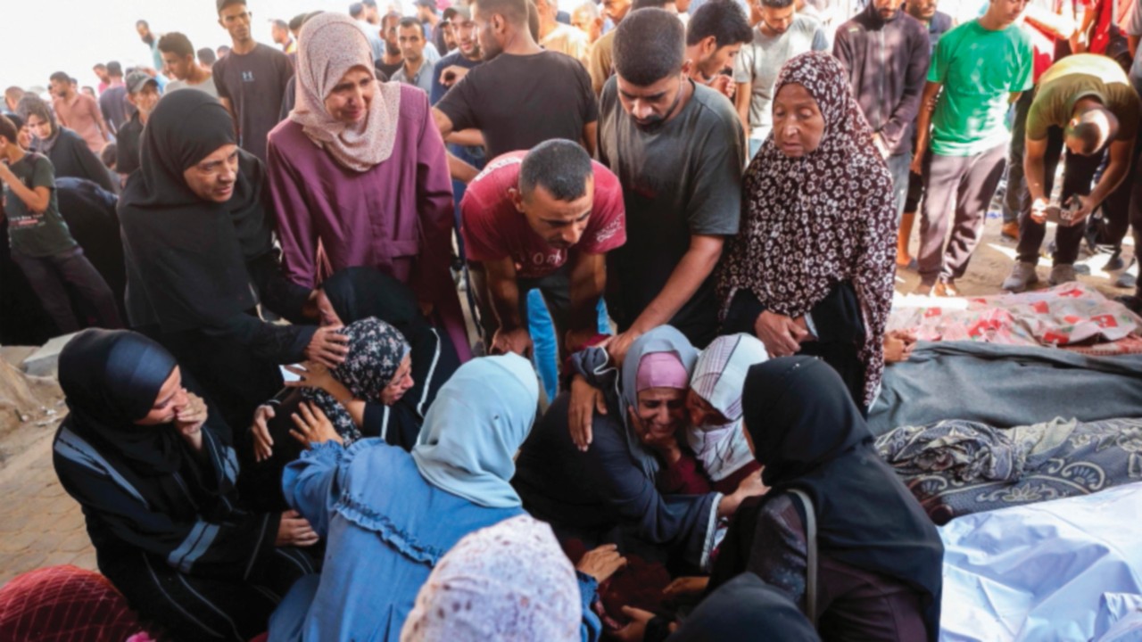 Palestinians mourn by the shrouded bodies of relatives killed in Israeli strikes on Gaza City at ...