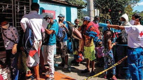 Venezuelan migrants wear a face masks as they queue to receive food and medicines from members of ...