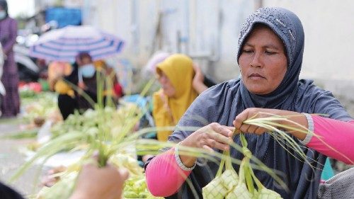 epa09352861 Indonesian woman make and sell traditional plaited coconut leaves containers for ketupat ...