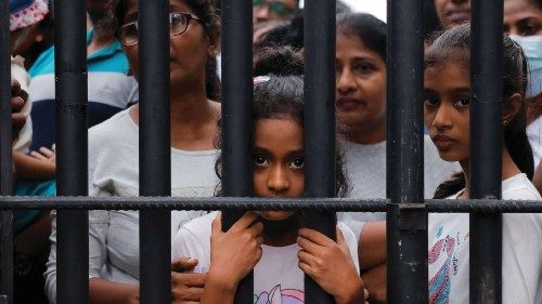 People wait behind a gate to visit the President's house on the day after demonstrators entered the ...