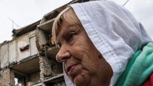 A woman stands in front of a destroyed building, with her apartment on its second floor, as Russia's ...