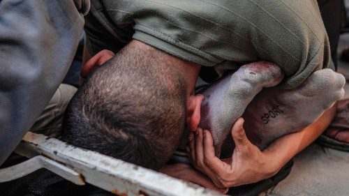 TOPSHOT - A Palestinian man hugs the feet of a victim of Israeli bombardment in Maghazi, in the ... TOPSHOT - A Palestinian man hugs the feet of a victim of Israeli bombardment in Maghazi, in the ...