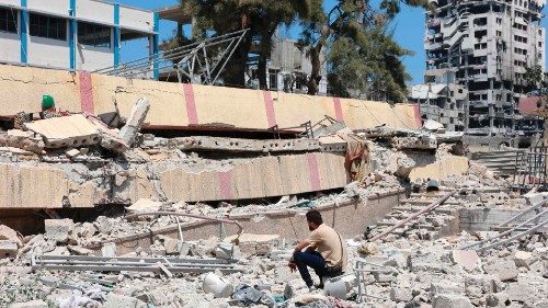 TOPSHOT - A man looks at the debris after an Israeli strike on a school, housing displaced ...