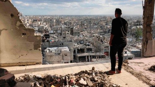 A man standing atop a heavily damaged building views other destroyed buildings in Khan Yunis in the ... A man standing atop a heavily damaged building views other destroyed buildings in Khan Yunis in the ...