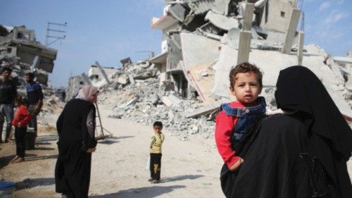 A Palestinian woman carries a child as they walk past the rubble of houses destroyed in previous ... A Palestinian woman carries a child as they walk past the rubble of houses destroyed in previous ...