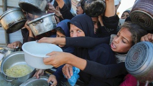 Palestinians gather to receive food cooked by a charity kitchen, amid a hunger crisis, as the ...