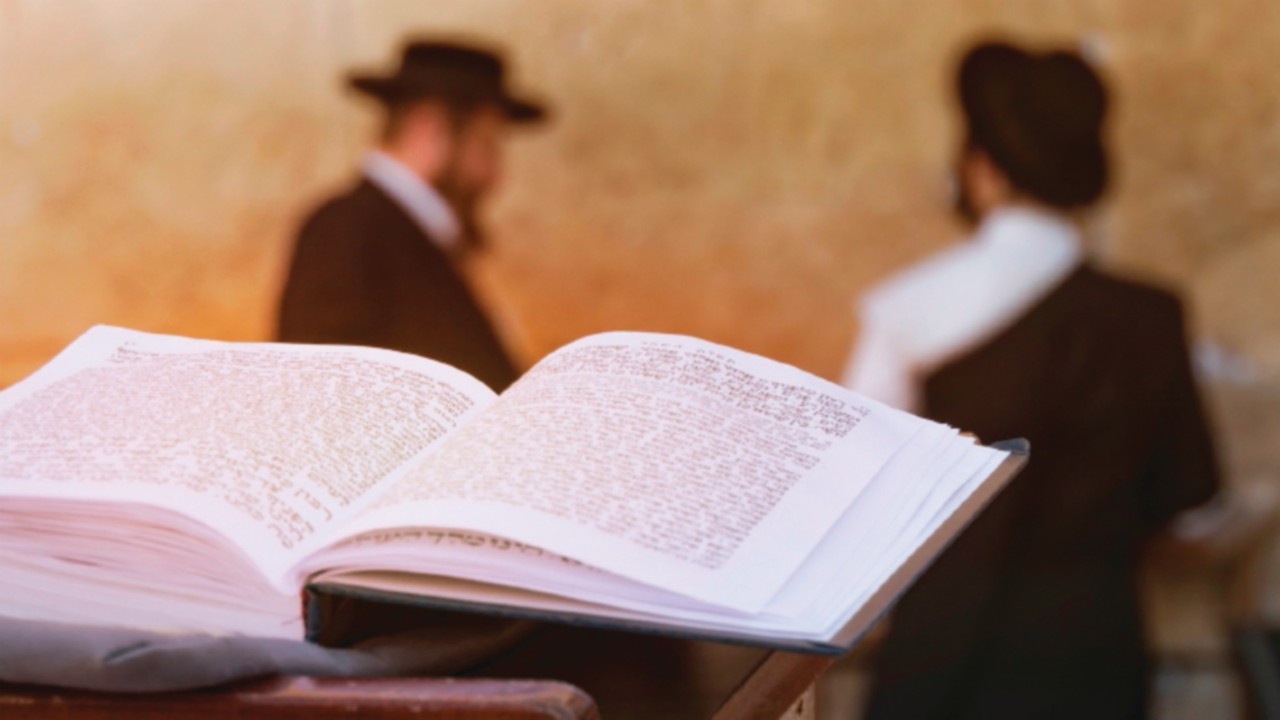 book of the Torah - Pentateuch of Moses is open on the prayer table on the background of praying ...