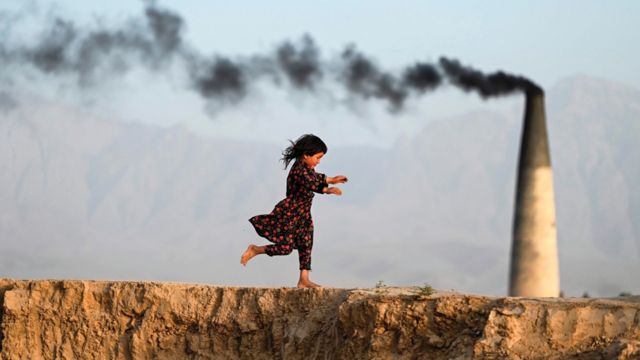 TOPSHOT - An Afghan girl runs across a brick kiln on the outskirts of Mazar-i-Sharif on June 22, ...